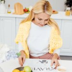 Attrayant blonde mature femme lecture journal de voyage à la cuisine