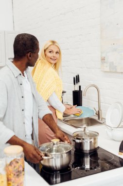 Afrika kökenli Amerikalı adam pot kadın mutfakta bulaşık süre tutan