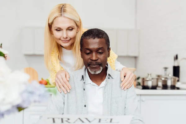 Donna Matura Sorridente Che Abbraccia Uomo Africano Americano Mentre Legge — Foto stock gratuita