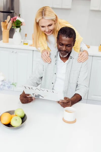 Mujer Sonriente Madura Abrazando Hombre Mientras Lee Periódico Viaje Cocina — Foto de stock gratis