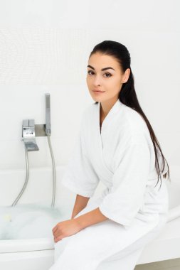Güzel kadın beyaz banyo beyaz bornoz oturuyor 