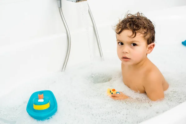 Piccolo Ragazzo Con Giocattoli Bagno Bagno Bianco Con Schiuma Bolle — Foto stock gratuita