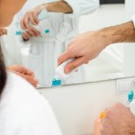 Recortado vista de hombre añadiendo pasta de dientes en mujer cepillo de dientes