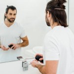 Man holding shaving foam and looking in mirror