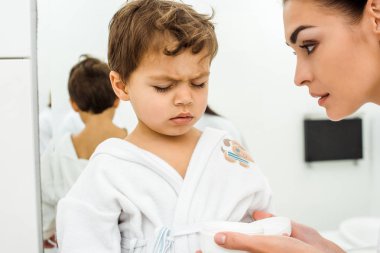 yüz krem beyaz bornoz kapalı gözlerle oturan oğlu süre tutan anne