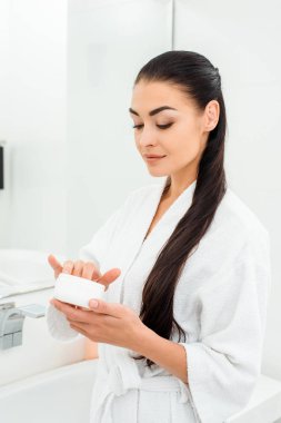 yüz kremi banyoda holding beyaz bornoz güzel kadın