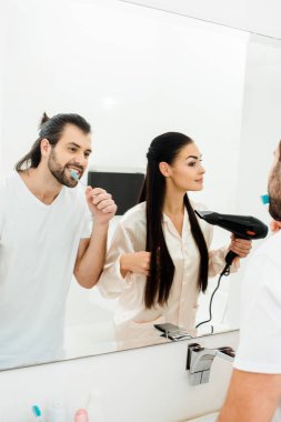 yakışıklı yetişkin adam sırasında karısı saç kurutma makinesi ile saç kurutma diş fırçalama 