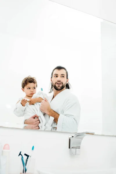 Dad Son Looking Mirror White Bathrobes Holding Toothbrushes — Free Stock Photo
