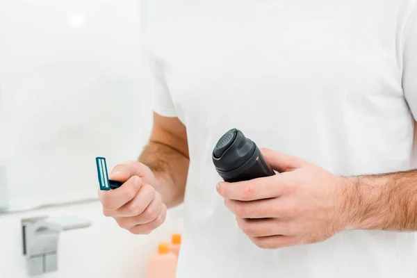 Man holding in hands safety razor and shaving foam