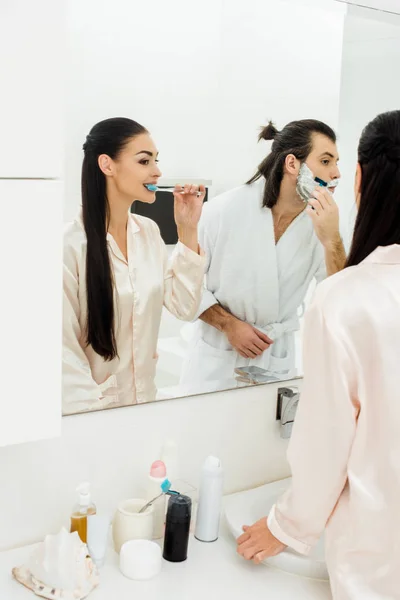 Beautiful Woman Brushing Teeth Handsome Man Shaving Front Mirror Bathroom — Free Stock Photo