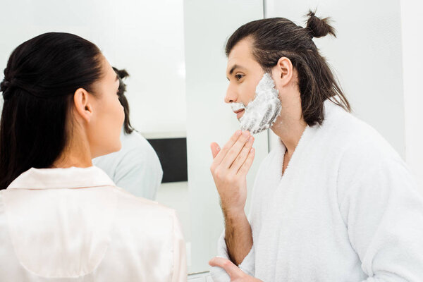 Handsome man shaving in front of lovely wife