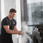 Handsome muscular bodybuilder applying talcum powder before training with tire in gym