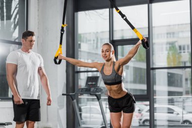 eğitmen ile süspansiyon askıları spor salonunda egzersiz sporcumuz bakarak