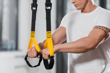 dövmeli atletik vücut geliştirmeci süspansiyon askıları spor salonunda holding resim kırpılmış