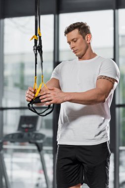 spor salonunda süspansiyon askıları tutan yakışıklı atletik vücut geliştirmeci