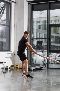 spor salonunda yakışıklı atletik vücut geliştirmeci ile çalışma dışarı yan görünüm ipleri