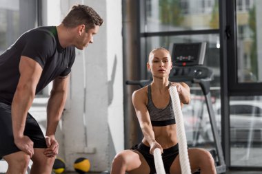 ipleri spor salonunda, ona bakmayı eğitmen ile çalışma dışarı çekici atletik vücut geliştirmeci