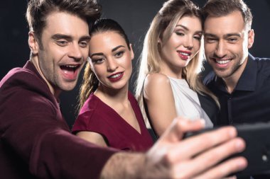 close-up shot of group of friends taking selfie with smartphone during party on black clipart