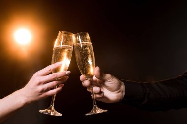 cropped shot of couple clinking glasses of champagne under golden light clipart