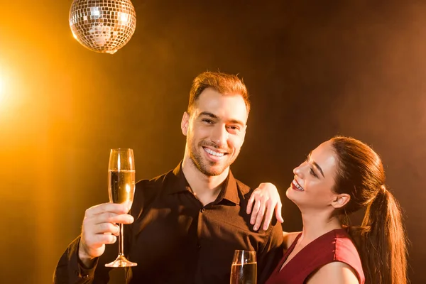 Šťastný Mladý Pár Drží Šampaňské Pod Zlatým Světlem — Stock fotografie zdarma