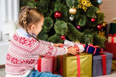 şirin çocuk Noel ağacının altında hediye kutuları açma yan görünüm