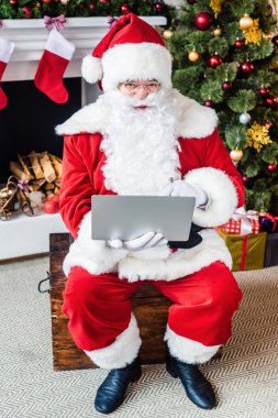 dizüstü bilgisayar kullanarak ve kameraya bakarak Claus santa yüksek açılı görünüş 