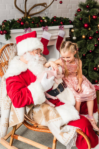 high angle view of santa claus and cute little child playing with adorable pig at christmas time