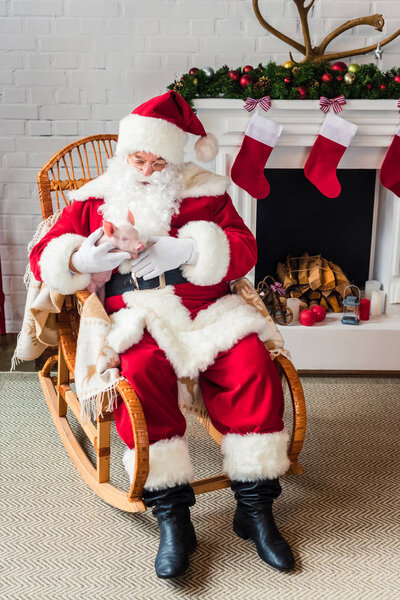 high angle view of santa claus holding pig and sitting in rocking chair