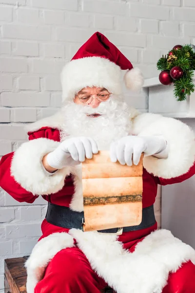 Santa Claus Siedzi Klatce Piersiowej Trzymając Pergamin Listy Ulubionych — Zdjęcie stockowe