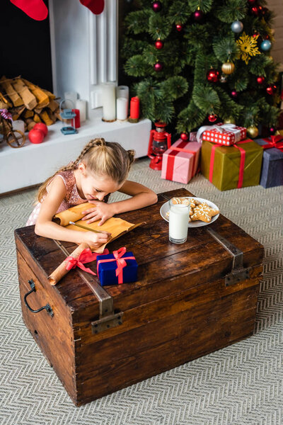 high angle view of adorable little child writing wishlist on parchment at christmas time