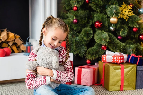 クリスマスイブの日にくまのぬいぐるみで遊んでかわいい幸せな子供 — ストック写真