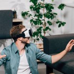 Enfoque selectivo de hombre joven usando auriculares de realidad virtual en casa