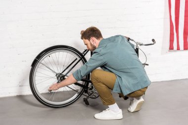Genç adam tarafından ayarlanabilir anahtarı Bisiklet tamir yan görünüm 