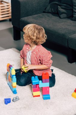 renkli plastik bloklarla pistinde evde oynayan kıvırcık küçük çocuk yüksek açılı görünüş
