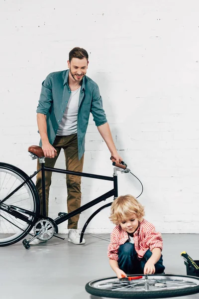 Adorable Little Boy Fixing Wheel Pliers While His Father Standing — Stock Photo, Image