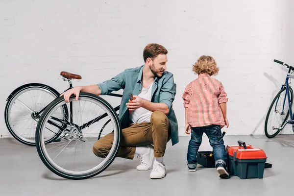 Selective Focus Male Repairman Sitting Bicycle Wheel Looking Son Standing — Stock Photo, Image