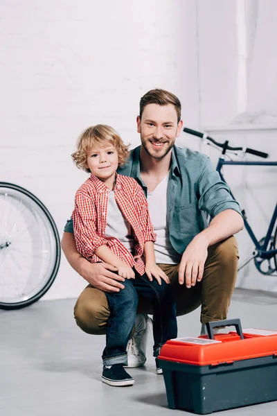 Glücklicher Mann Sitzt Mit Kleinem Sohn Neben Werkzeugkiste Fahrradwerkstatt — Stockfoto