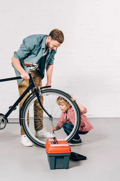 Criança Seu Pai Reparando Roda Bicicleta Perto Caixa Ferramentas Oficina — Fotos gratuitas