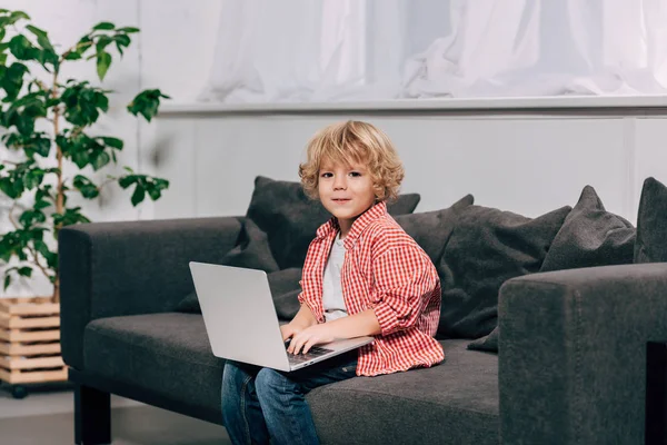 Pequena Criança Olhando Para Câmera Usando Laptop Sofá Casa — Fotografia de Stock Grátis