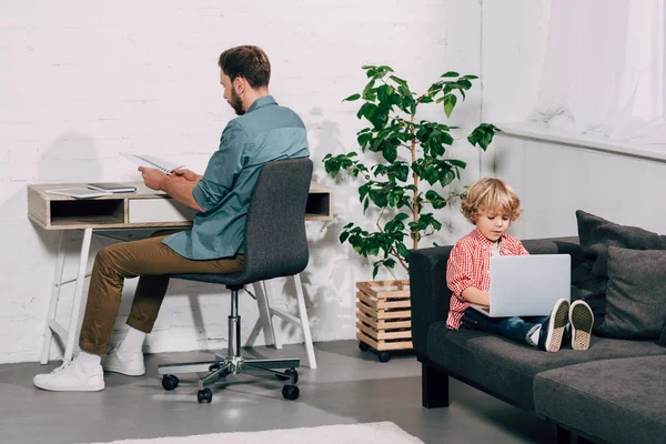 Tinggi Sudut Pandang Anak Kecil Menggunakan Laptop Sofa Sementara Ayahnya — Stok Foto