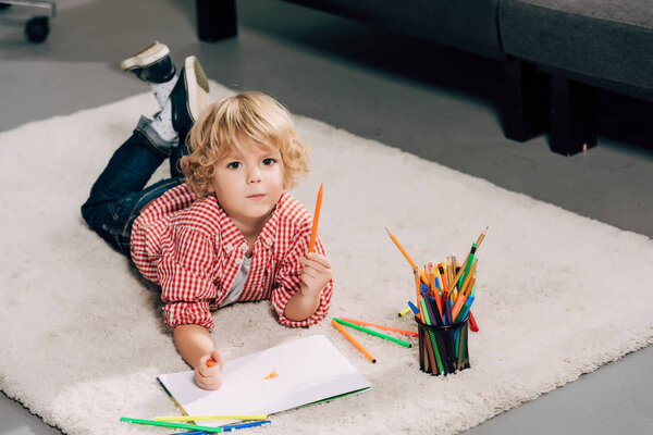 high angle view of adorable little boy drawing by marker at home