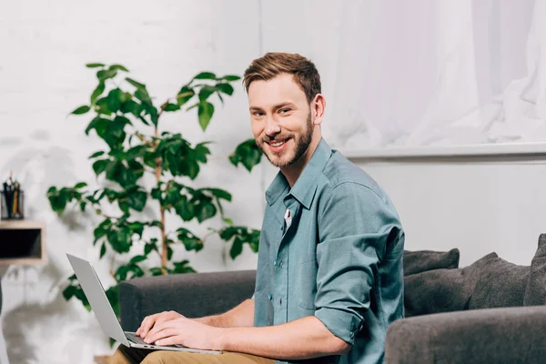 Śmiejąc Się Młody Mężczyzna Freelancer Pracuje Laptopie Kanapie Domu — Zdjęcie stockowe