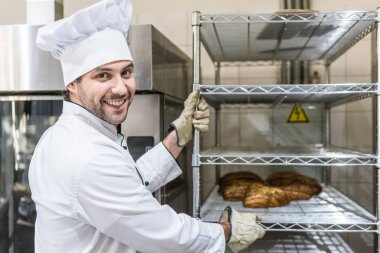 Erkek baker ile sıcak ekmek raf üzerinde gülümseyen