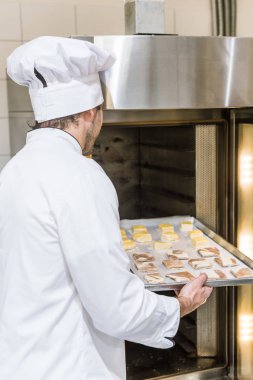 Fırın tepsisi ile pişmemiş hamur fırında koymadan Beyaz şefler üniformalı erkek baker