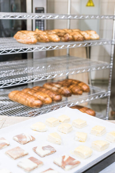 fresh baked bread on rack and raw dough pieces on baking paper at kitchen