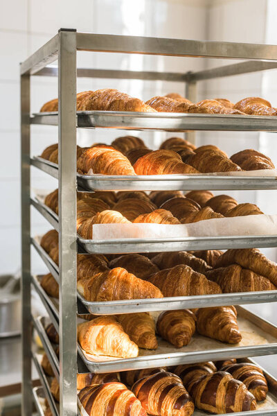 golden french croissants on baking trays at kitchen rack