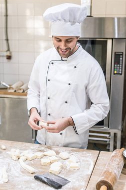 Profesyonel mutfak at pişmemiş hamur ile gülümseyen baker