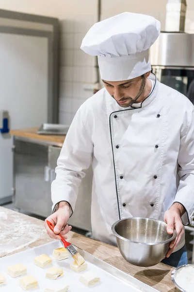 Mâle Boulanger Huiler Des Morceaux Pâte Avec Brosse Badigeonner Cuisine — Photo gratuite