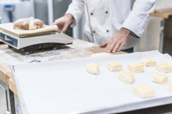 Cropped view of baker weighing dough on kitchen scales