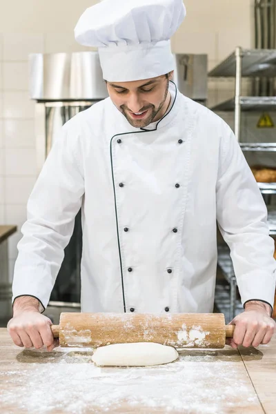 Uśmiechający Się Baker Toczenia Niegotowanego Ciasta Drewnianym Stole — Darmowe zdjęcie stockowe